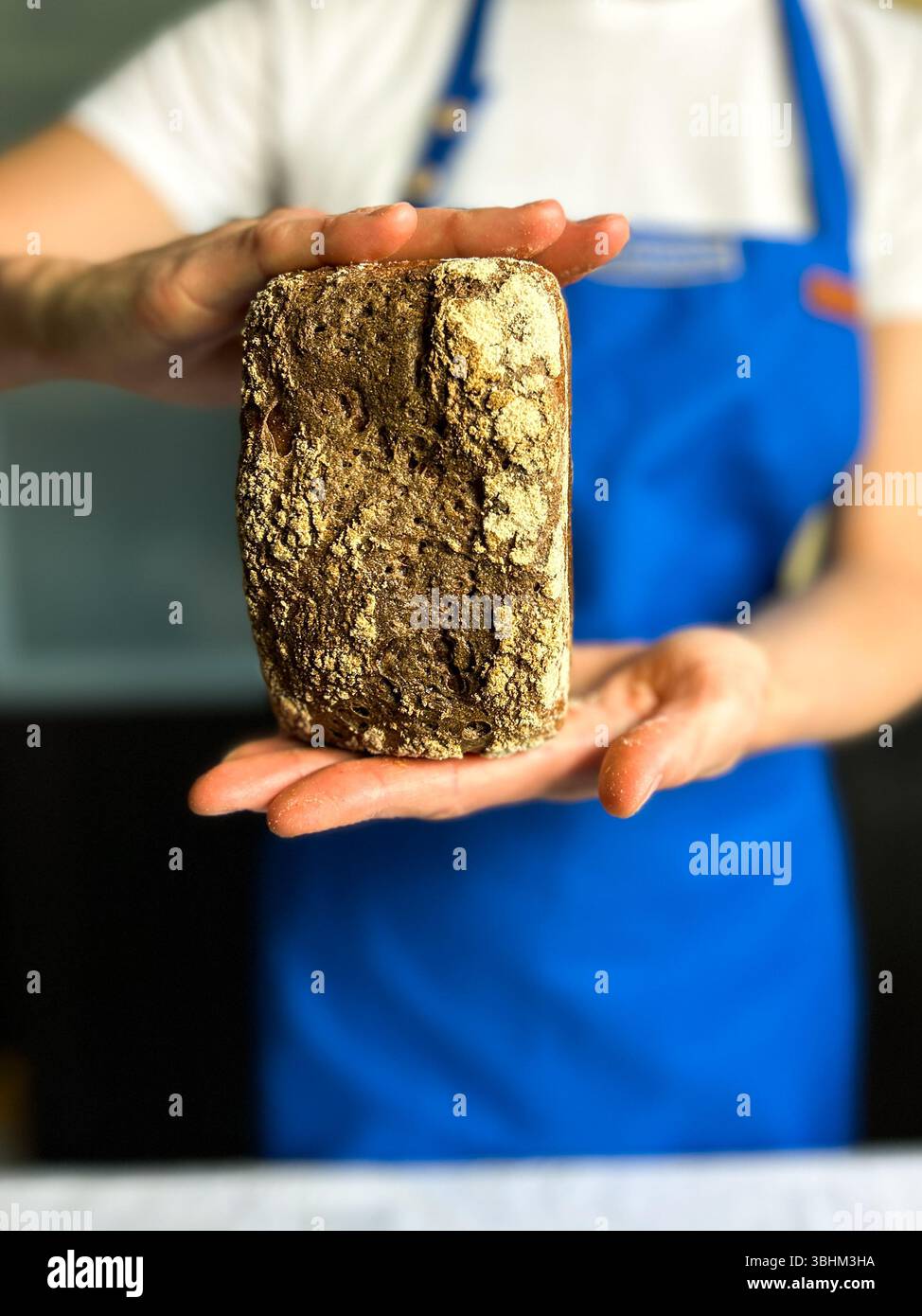 Femme tenant un pain de levain fraîchement cuit au four fait avec du starter sans gluten. Parfait pour les blogs de cuisson saine, les marques d'aliments biologiques et la boulangerie artisanale Banque D'Images