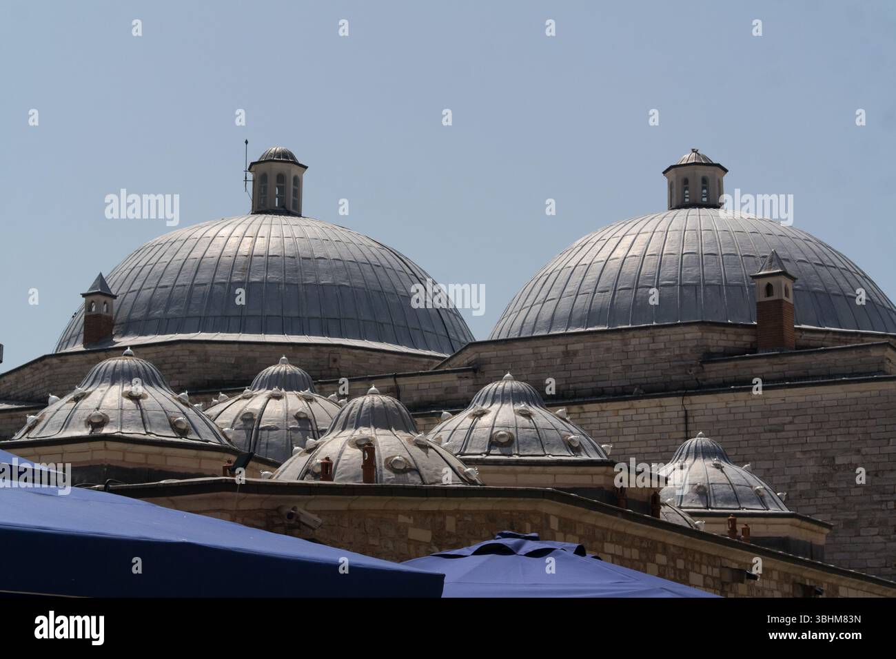 Les visiteurs admirent les dômes complexes et les détails architecturaux d'un bâtiment historique d'Istanbul sous un ciel bleu clair. Banque D'Images
