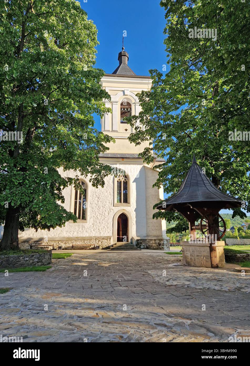 Vieux puits traditionnel en bois et pierre et le clocher entouré de vieux chênes dans la cour du monastère de Capriana, République de Moldavie Banque D'Images