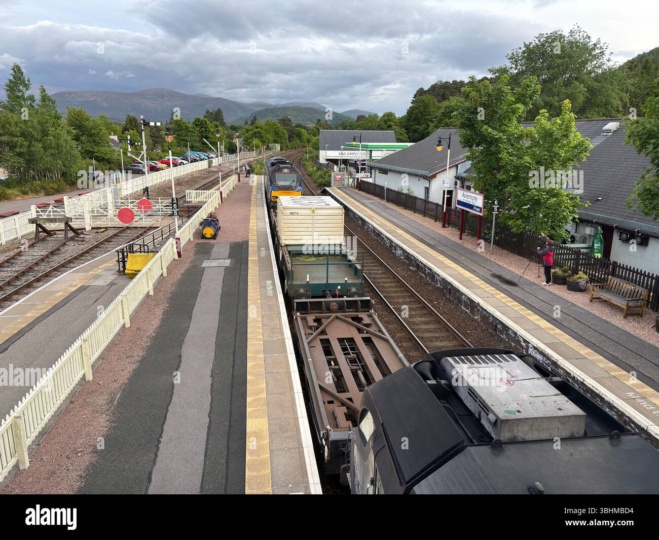 Un train de marchandises passe devant la gare d'Aviemore, transportant des marchandises à travers les Highlands, illustrant le transport rural vital et l'industrie. Banque D'Images