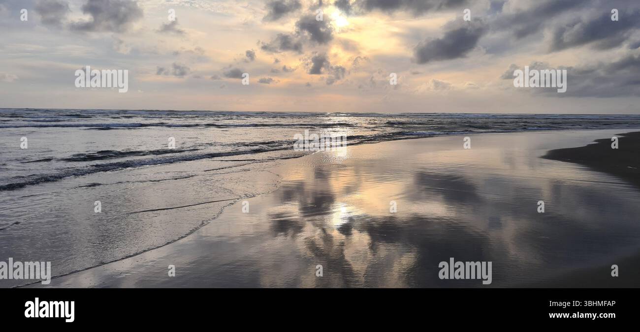 Coucher de soleil paisible sur l'océan Pacifique sur la côte de l'Oregon, États-Unis, avec des nuages spectaculaires et des reflets sur le sable humide. - Image de stock capturée avec un smartphone