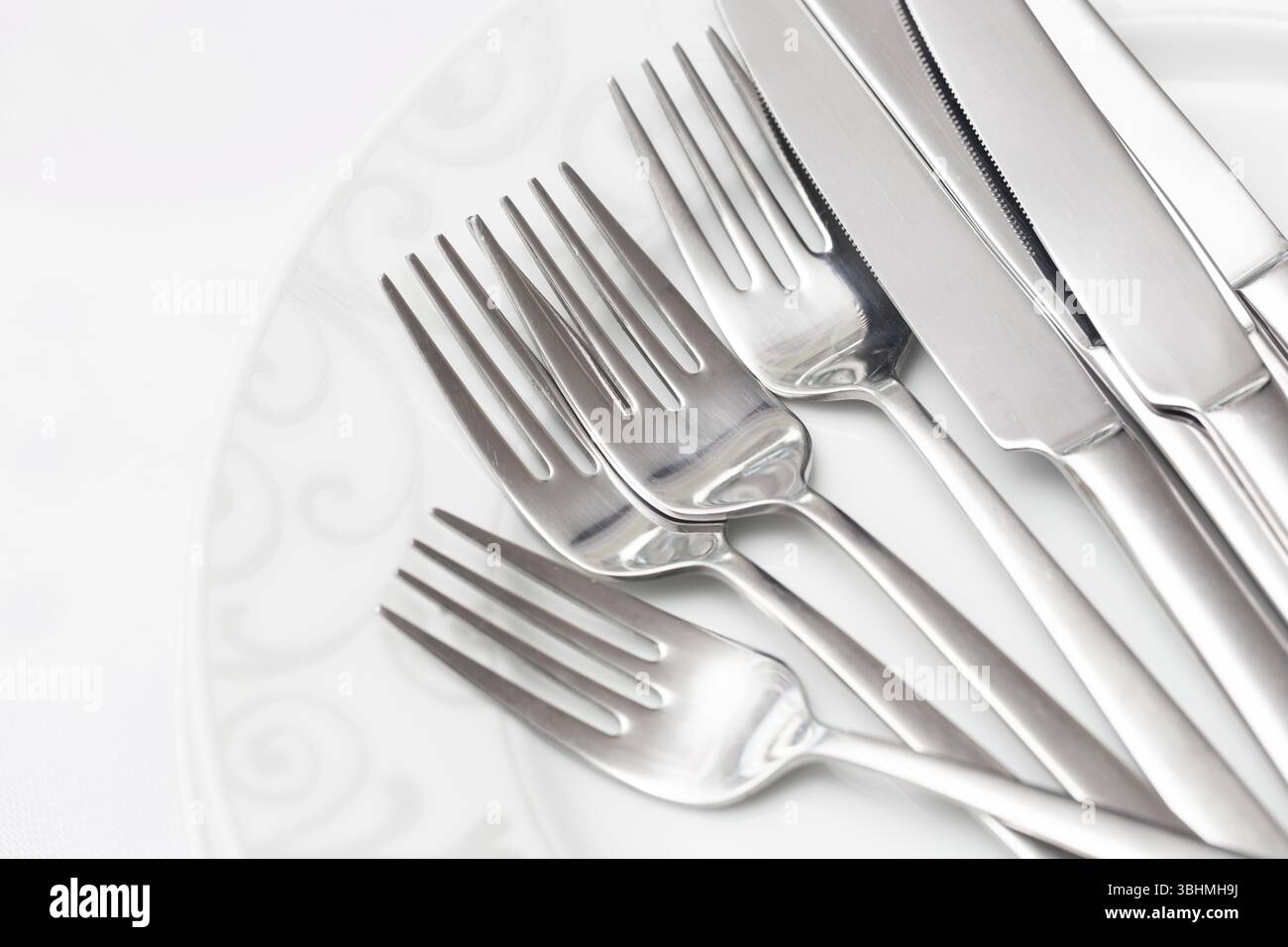 Couverts sur assiette blanche. Arrangement de fourchette et de couteau en argent. Table élégante. Ustensiles de cuisine pour les repas. Couverts brillants et polis. Banque D'Images
