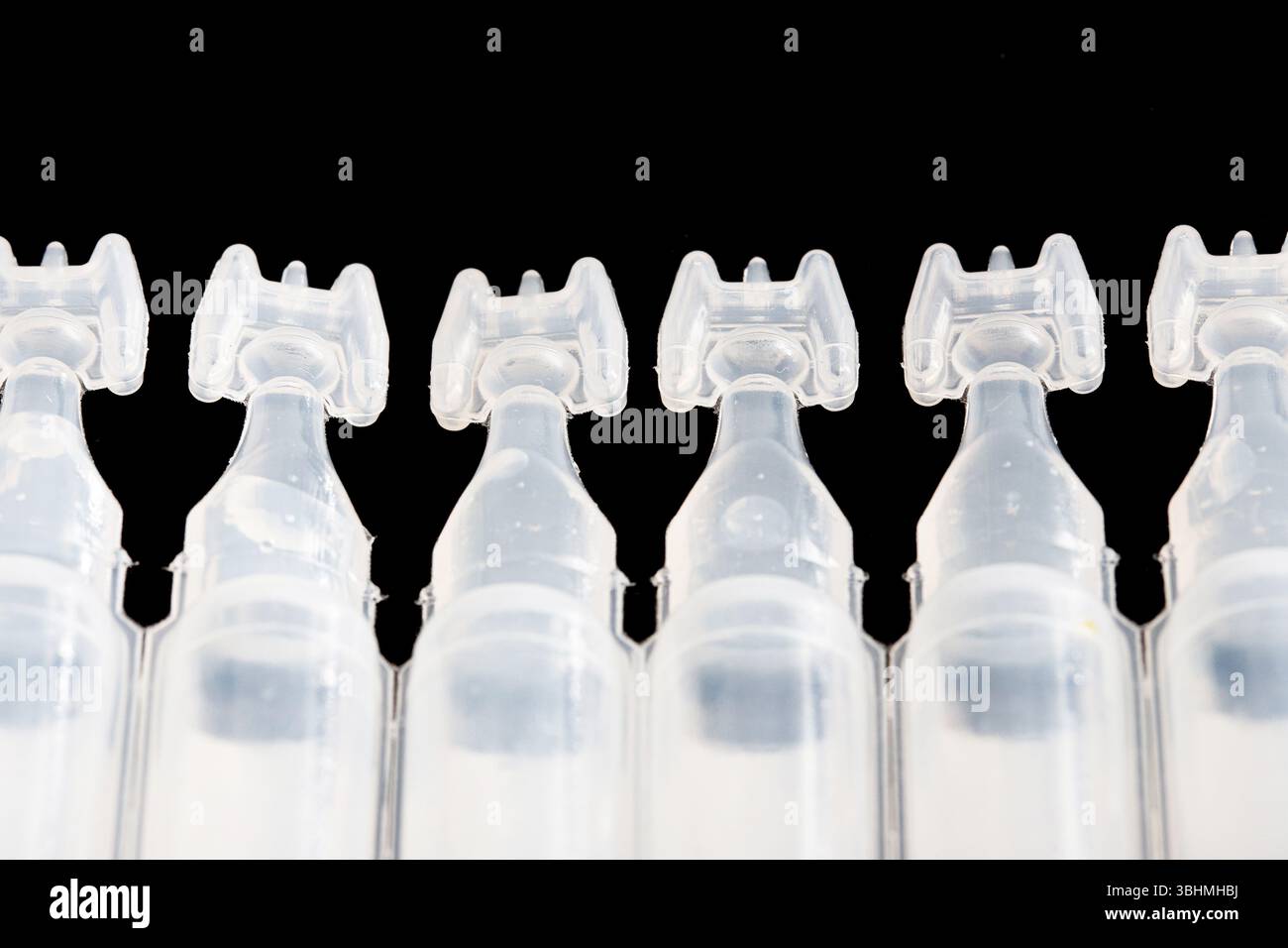 Ampoules en plastique dans la rangée sur fond noir. Emballage médical transparent. Récipients stériles à usage unique. Concept d'hygiène et de pharmacie. Banque D'Images
