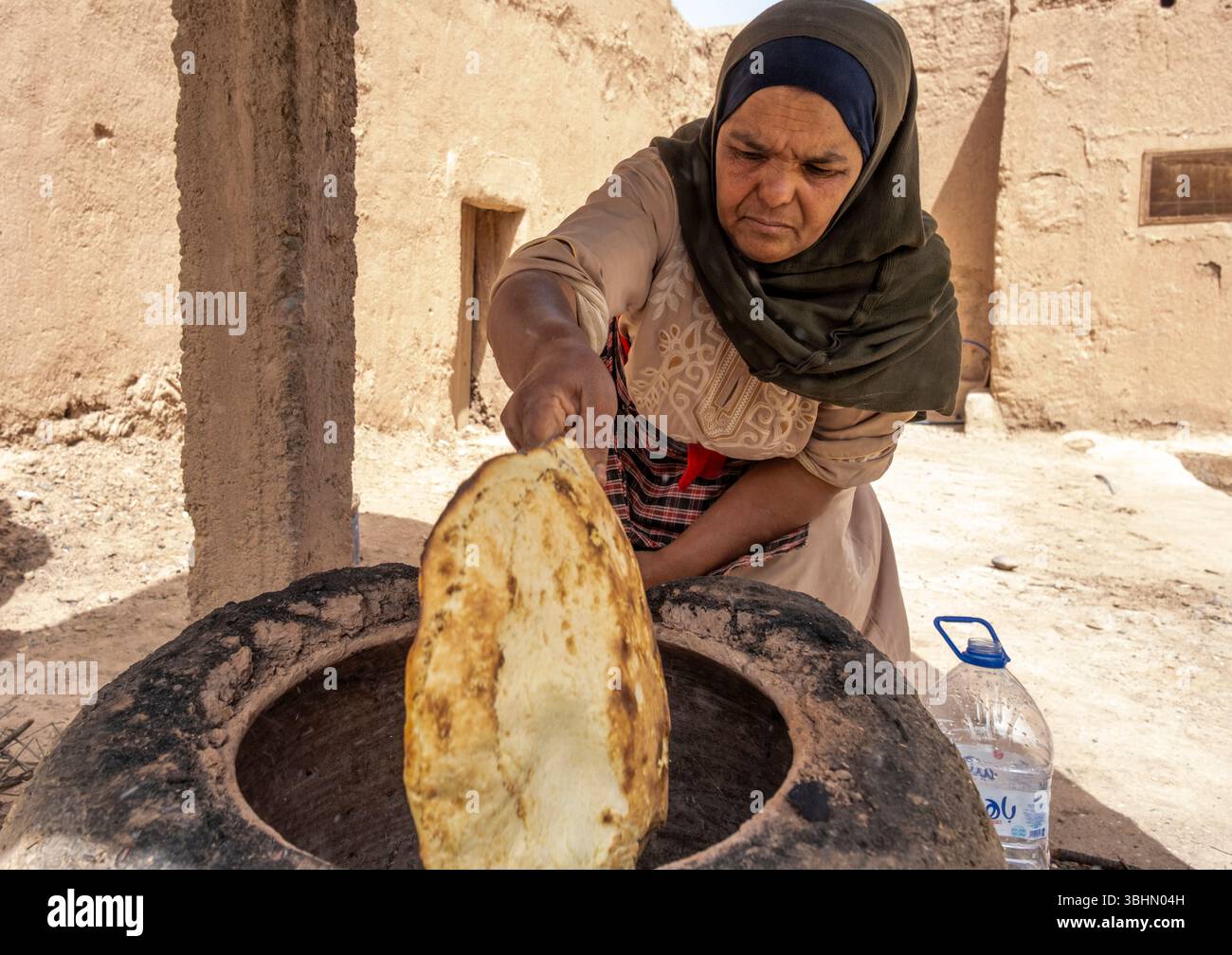 Une femme qui cuit du pain dans un four traditionnel. Skoura, province d'Ahl El Oust, Maroc. Banque D'Images