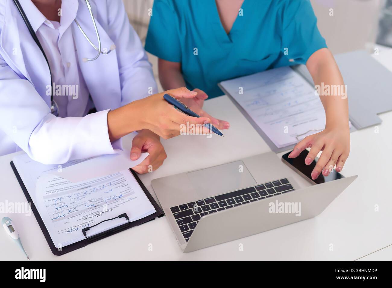 Les médecins adultes asiatiques collaborent sur les soins aux patients examinant des documents sur un ordinateur portable à leur bureau ils discutent de l'information sur la santé traitement p Banque D'Images