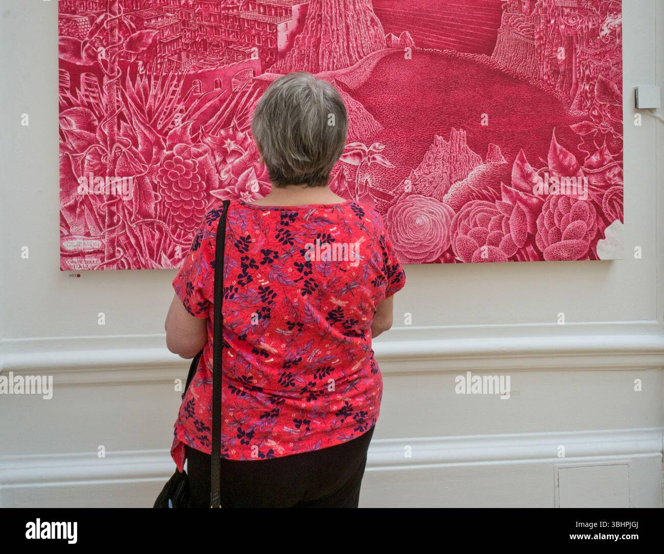 La femme visiteuse de l'exposition d'été de la Royal Academy porte un haut fleuri presque assorti à la peinture qu'elle regarde, Londres Royaume-Uni Banque D'Images