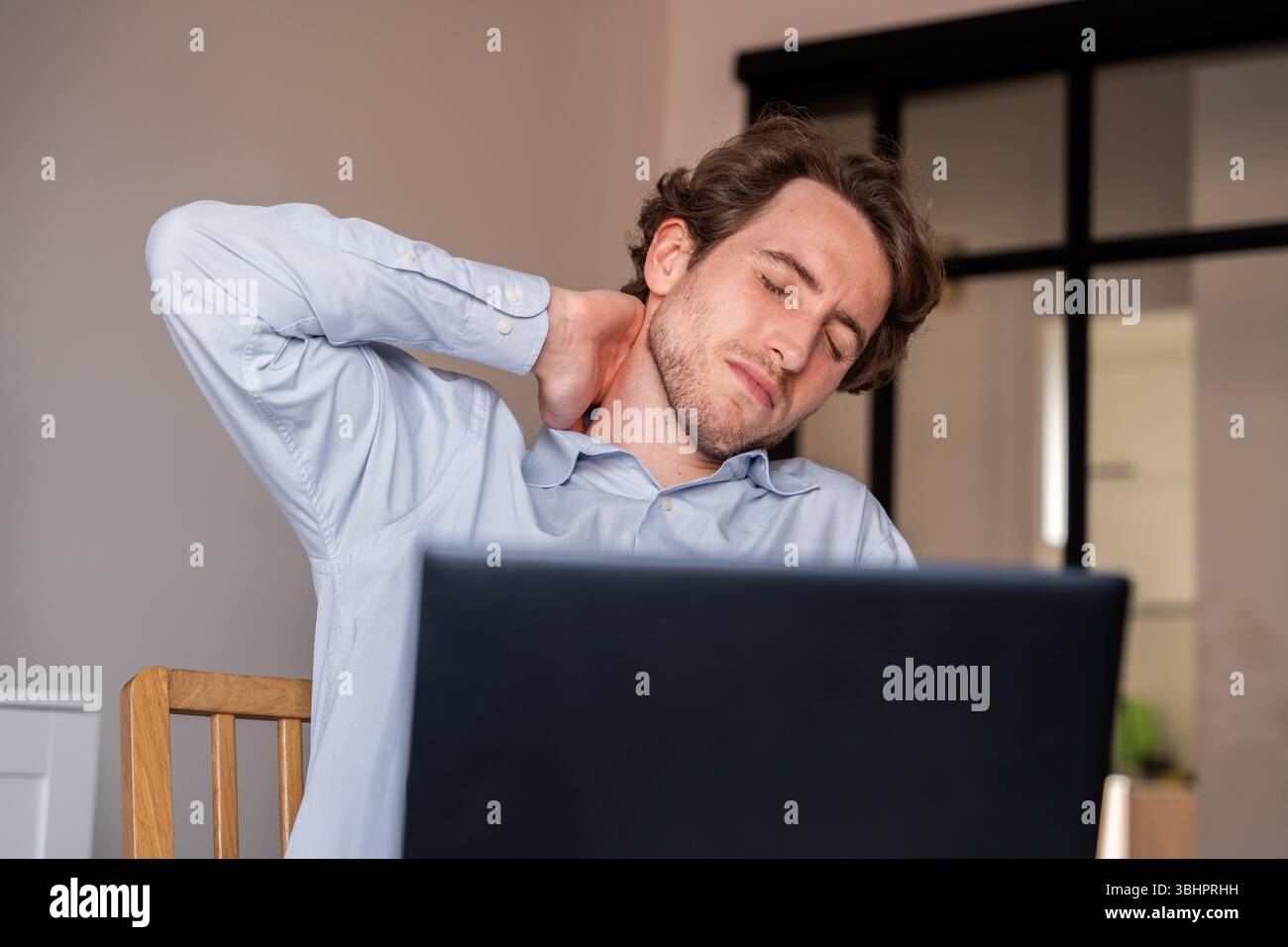 Homme assis étirant pendant le travail pour soulager la raideur musculaire Banque D'Images