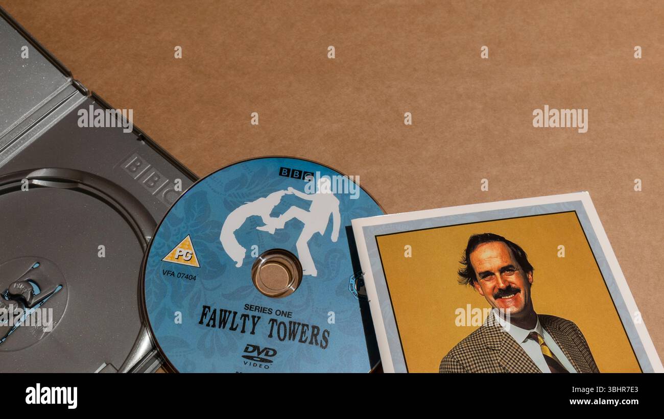 Une boîte DVD ouverte de Fawlty Towers, avec un disque DVD et un livret présentant Basil Fawlty. Banque D'Images