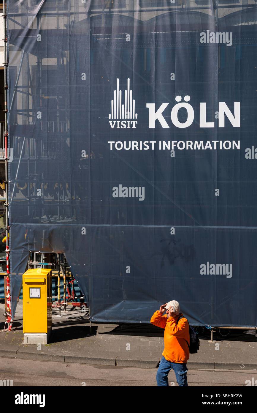 L'homme passe devant l'échafaudage du bâtiment d'information touristique près de la cathédrale, Koelntourismus, Cologne, Allemagne. Mann passiert die eingeruestete Tourisme I Banque D'Images