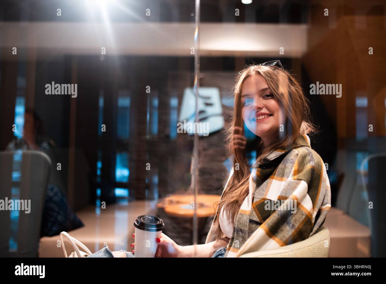 Femme élégante souriant derrière le verre dans le café Banque D'Images