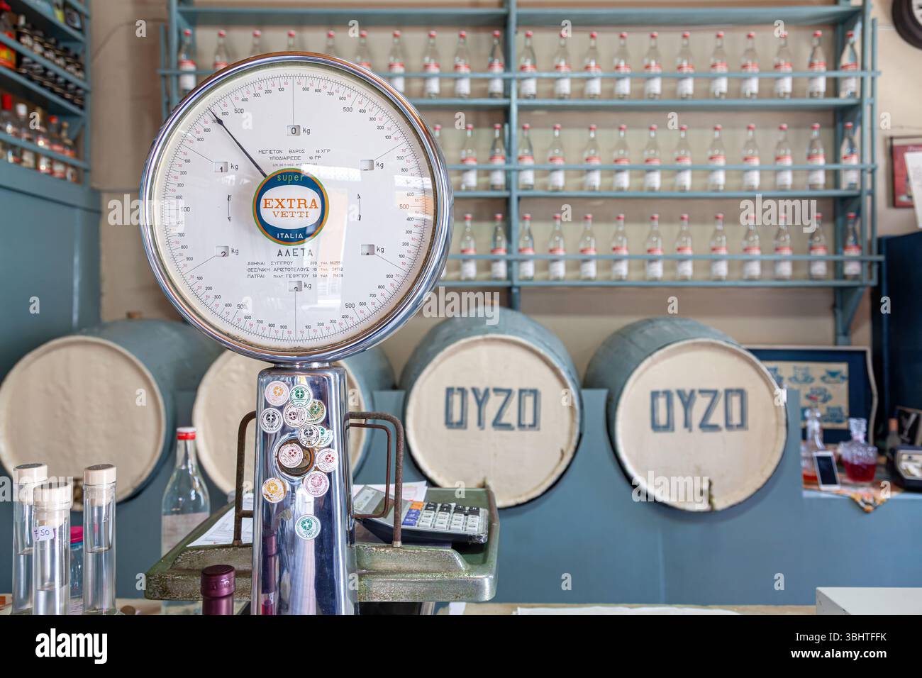 Des tonneaux d'ouzo et d'échelle vintage dans une distillerie grecque traditionnelle, entourés d'étagères de bouteilles mettant en valeur la production locale de spiritueux et le patrimoine. Banque D'Images