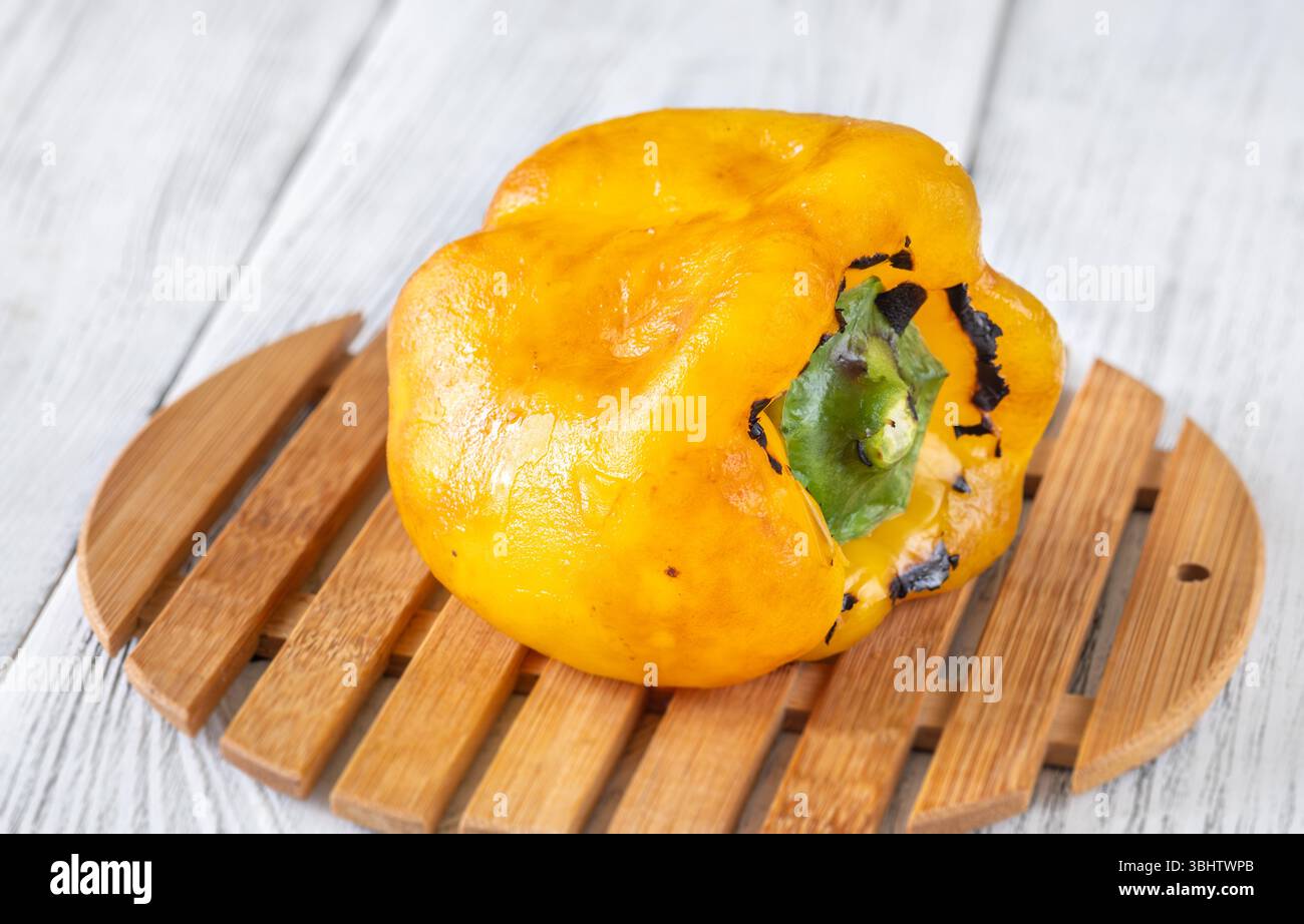 Le poivre jaune calciné scintille avec des marques de gril, reposant simplement sur du bois vieilli Banque D'Images