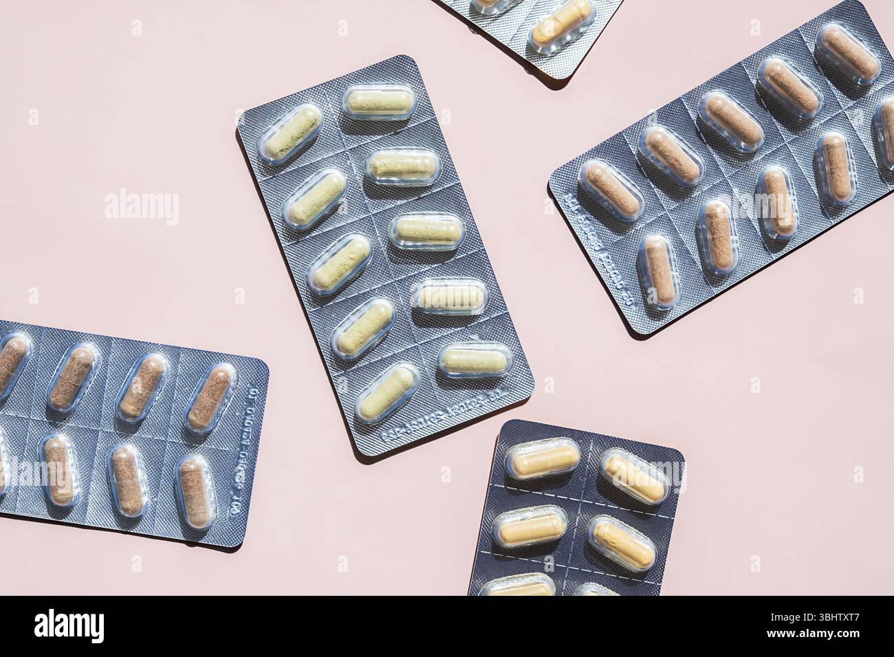 Plusieurs emballages sous blister remplis de capsule de dose translucide de médicament sur fond rose. Médicaments, pharmacie et concepts de santé. Banque D'Images