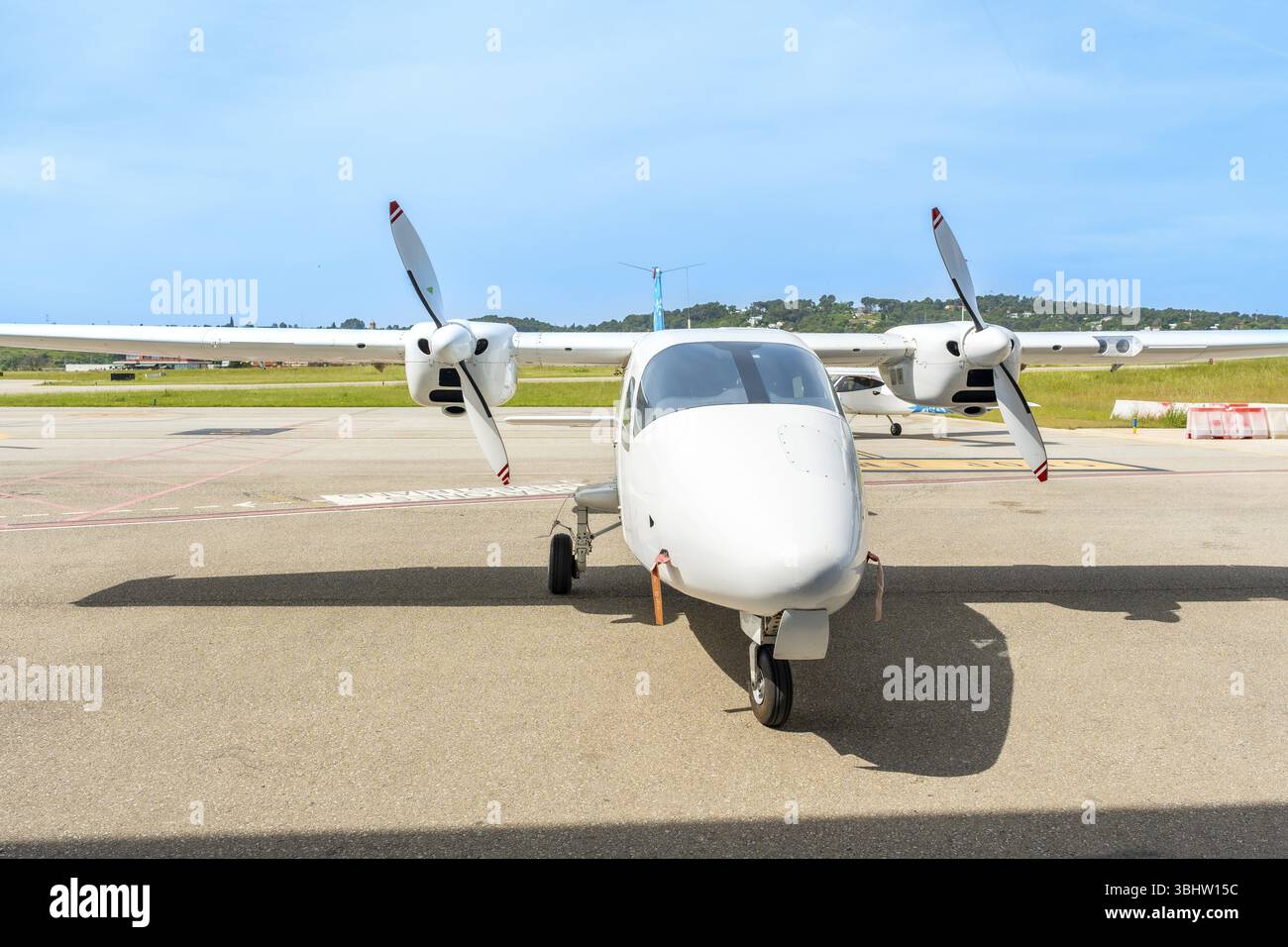 L'avion biturbopropulseur blanc est stationné sur le tarmac d'un petit aéroport par une journée ensoleillée, en attendant son prochain vol Banque D'Images