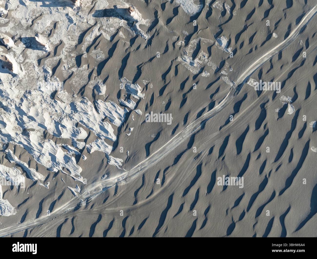 Vue aérienne du champ de pierre ponce et une route sale passant par un champ volcanique de sable noir, Puna, Catamarca, Argentine. Banque D'Images