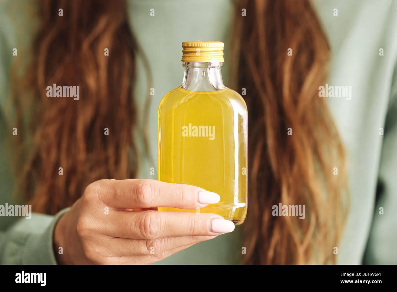 Petite bouteille d'alcool à la main. Liquide jaune transparent. Concept d'alcoolisme et d'addiction. Habitude dangereuse de boire. Contexte du problème de toxicomanie. Banque D'Images