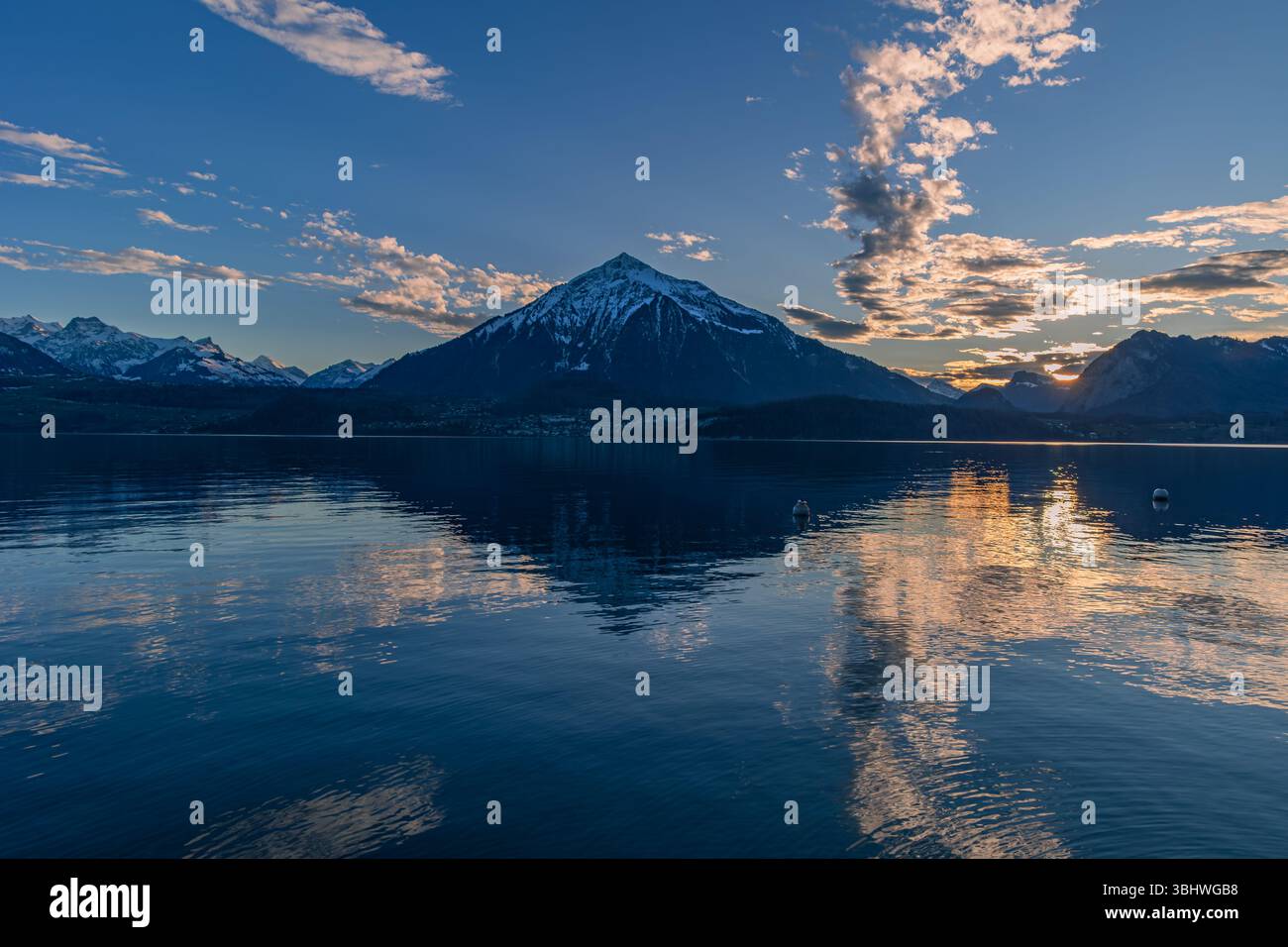 Coucher de soleil sur la montagne Niesen (appelée Pyramide suisse) avec son reflet de forme sur le lac de Thoune. Banque D'Images