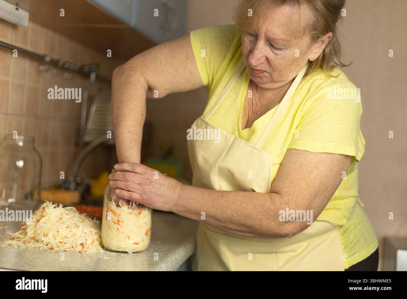 Fermentation à la maison — presser le mélange de chou et de carottes pour un marinage naturel. Banque D'Images