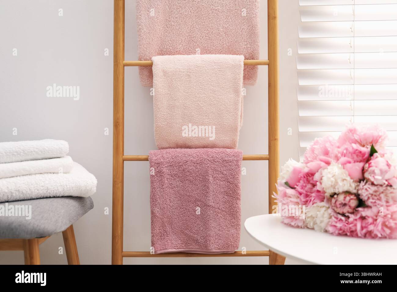 Serviettes douces sur l'échelle décorative en bois et fleurs de pivoine à l'intérieur Banque D'Images