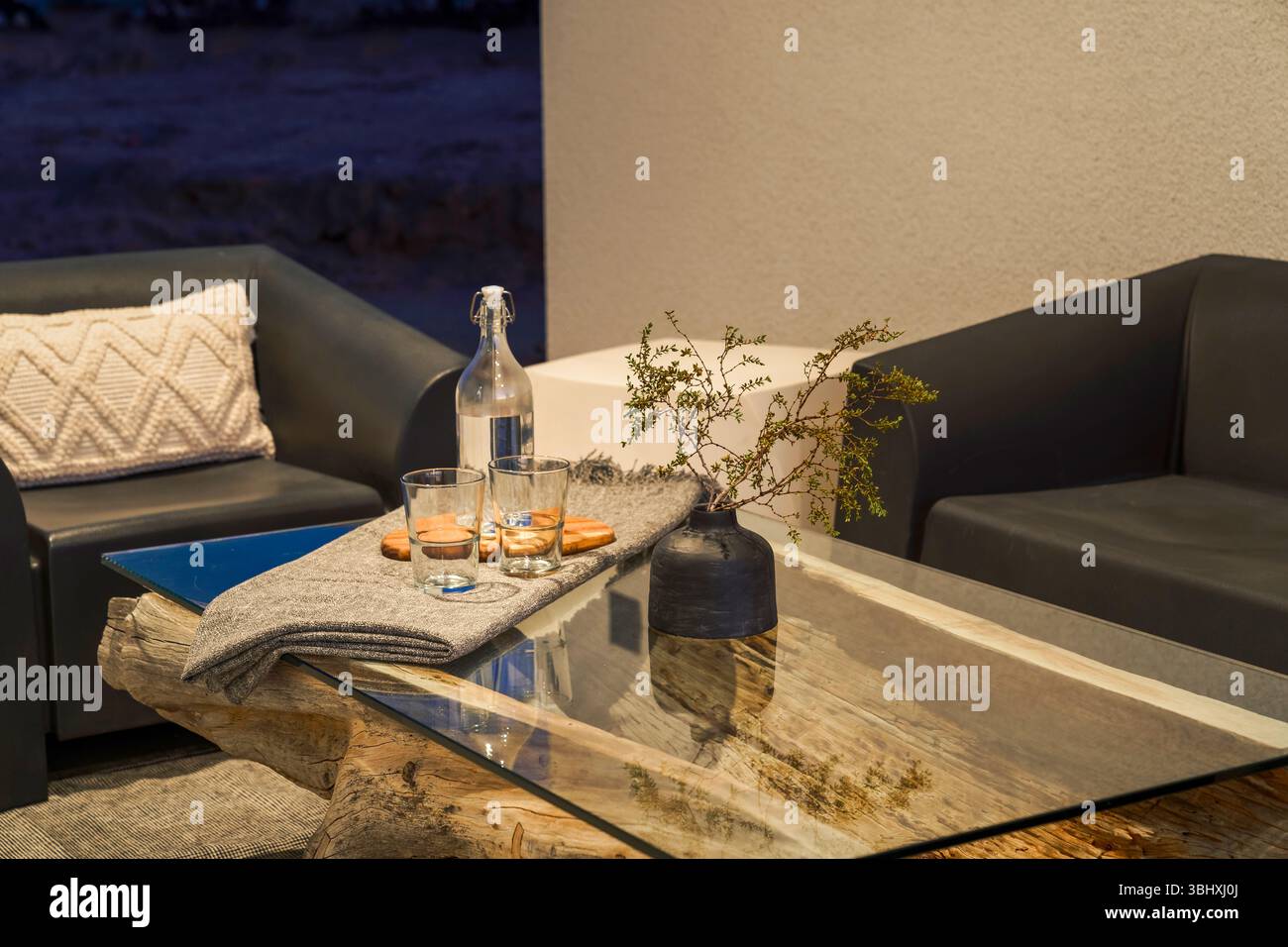 Table extérieure moderne verre verres bouteille d'eau, et vase la nuit à Joshua Tree, Californie extérieur Banque D'Images