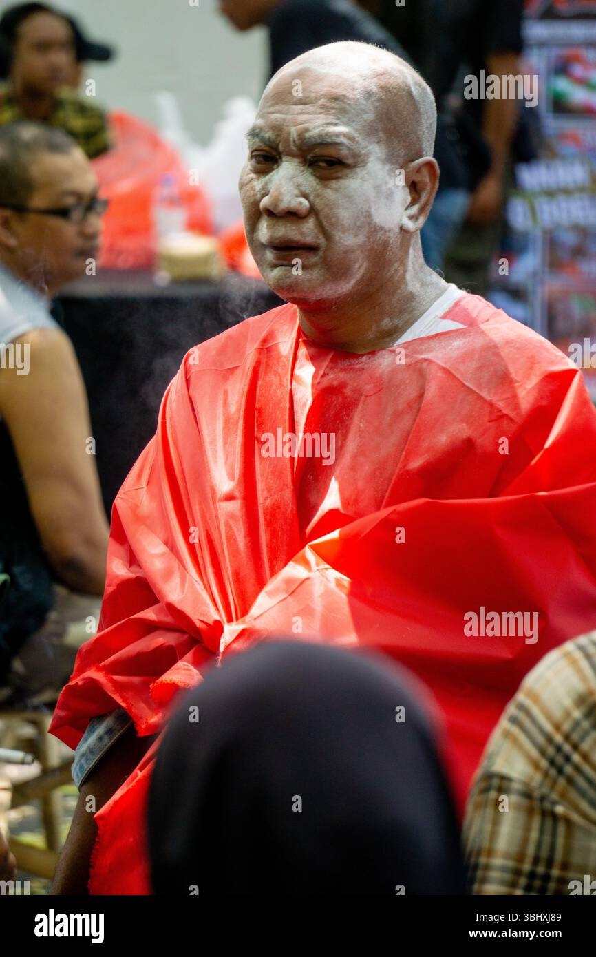 Le vieil homme chauve couvrit son corps d'un tissu rouge. Son visage était couvert de poudre blanche. Banque D'Images