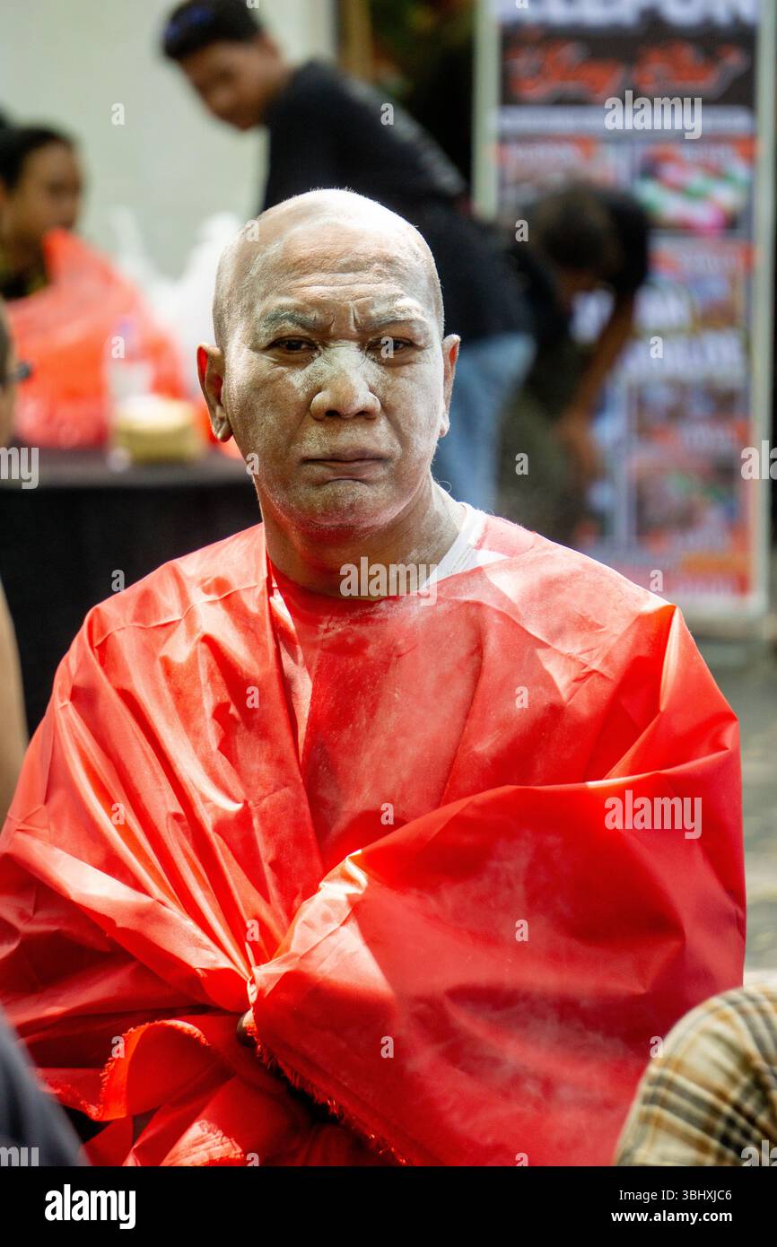 Le vieil homme chauve couvrit son corps d'un tissu rouge. Son visage était couvert de poudre blanche. Banque D'Images