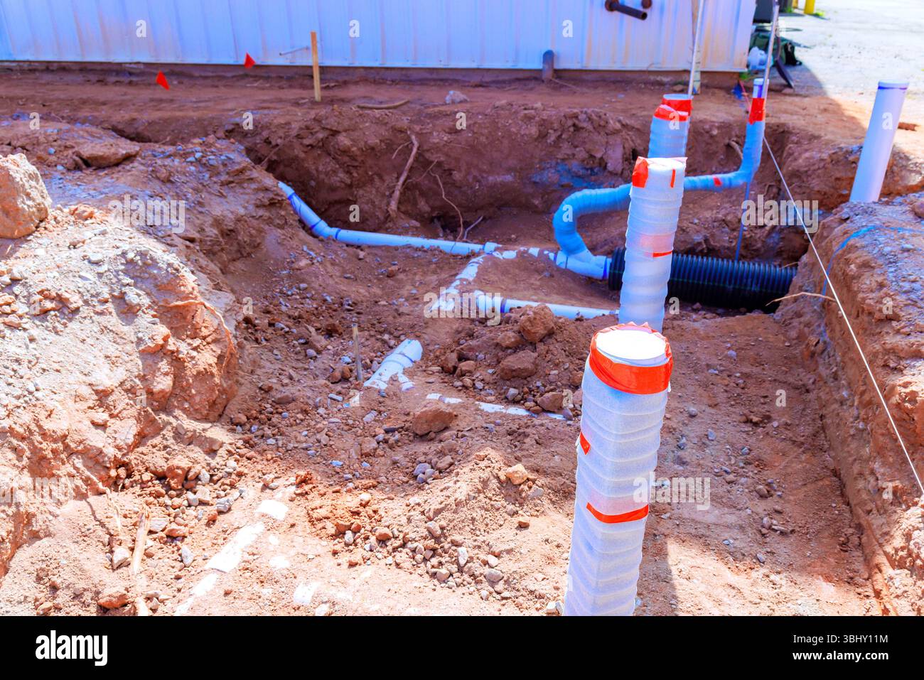 Les ouvriers creusent une tranchée pour de nouvelles lignes de plomberie dans le chantier de construction de banlieue en temps de travaux Banque D'Images