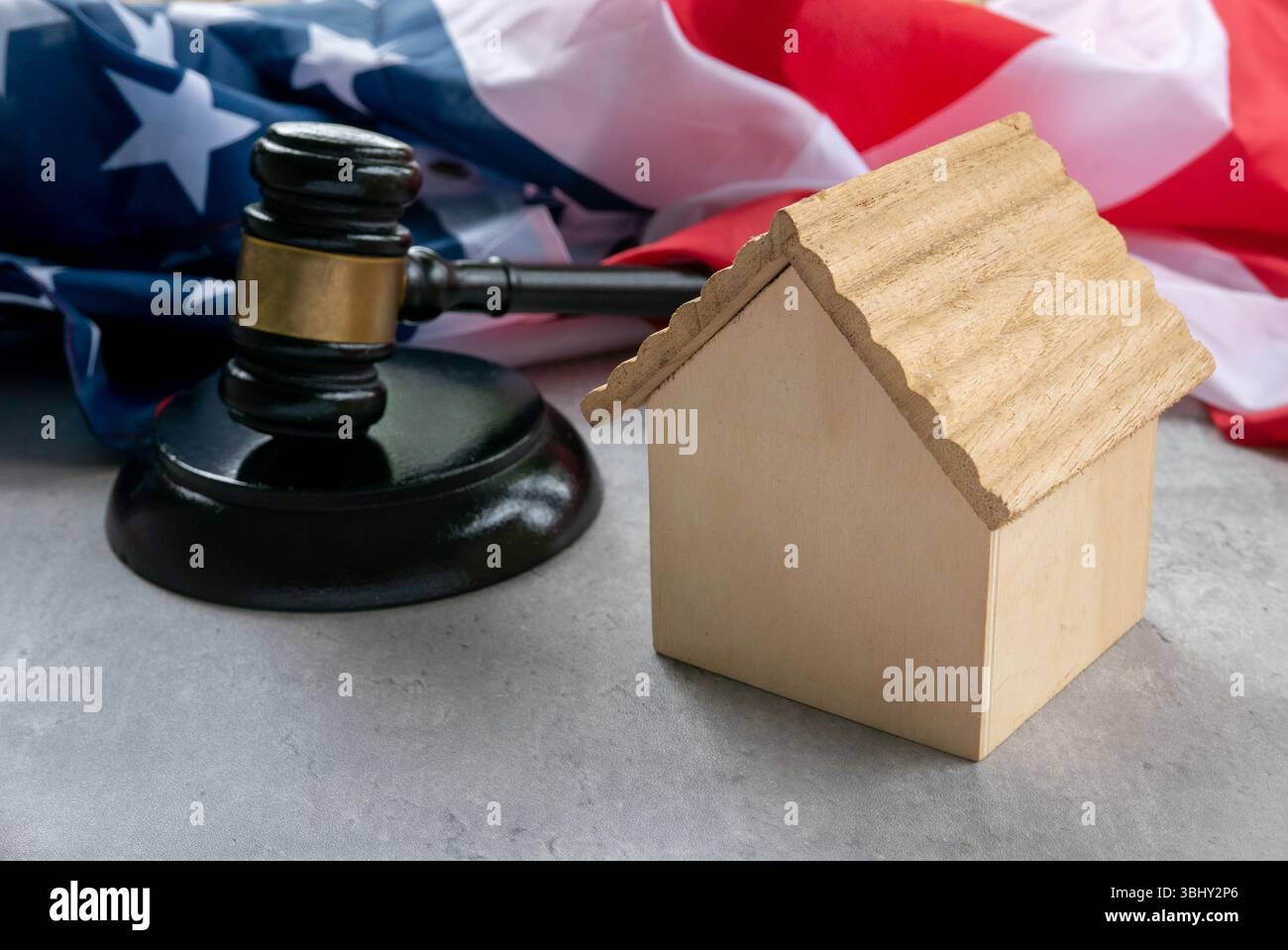 Drapeau américain avec Gavel et Toy Wooden House symbolisant les aspects juridiques de la propriété et des valeurs américaines Banque D'Images