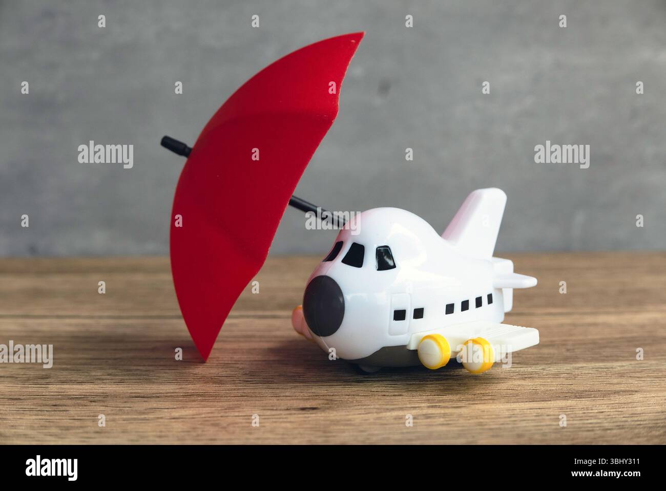 Avion jouet protégé sous parapluie rouge, symbolisant la sécurité et les soins Banque D'Images