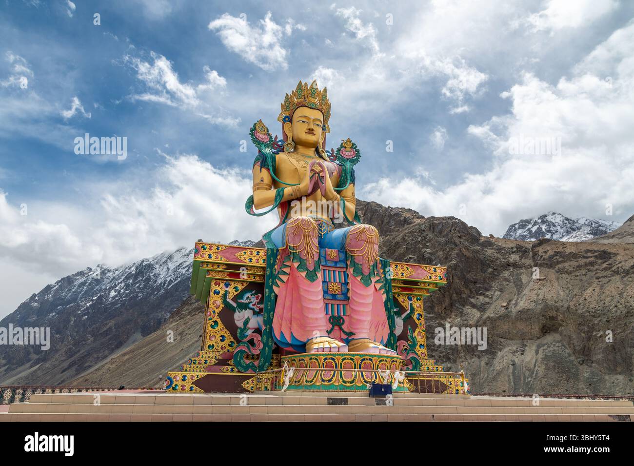 Majestueuse statue de Bouddha Maitreya au monastère Diskit, Ladakh, avec des sommets enneigés de l'Himalaya en arrière-plan, symbole de paix, de foi et de culture. Banque D'Images
