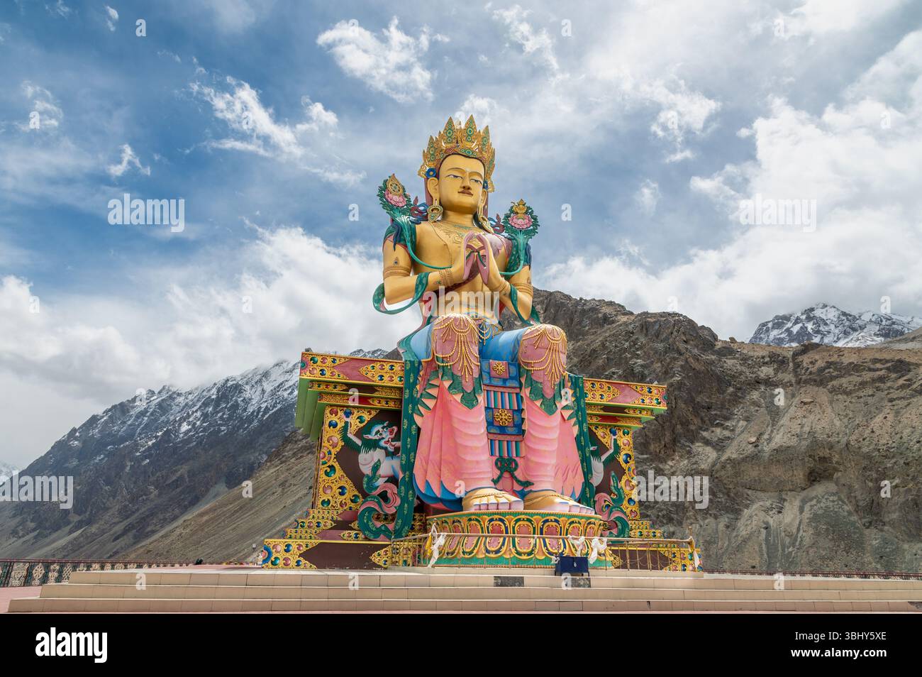 Majestueuse statue de Bouddha Maitreya au monastère Diskit, Ladakh, avec des sommets enneigés de l'Himalaya en arrière-plan, symbole de paix, de foi et de culture. Banque D'Images