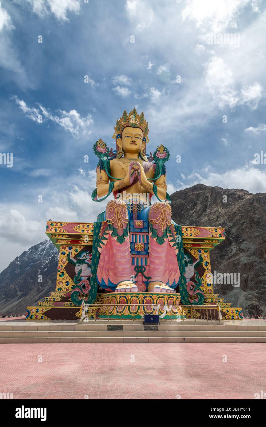 Majestueuse statue de Bouddha Maitreya au monastère Diskit, Ladakh, avec des sommets enneigés de l'Himalaya en arrière-plan, symbole de paix, de foi et de culture. Banque D'Images