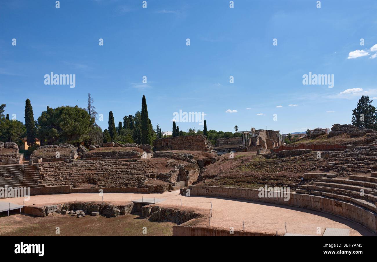 La vaste étendue des ruines de l'amphithéâtre romain de Mérida se déploie sous un ciel bleu vif, mettant en valeur les niveaux de pierre et l'arène centrale Banque D'Images