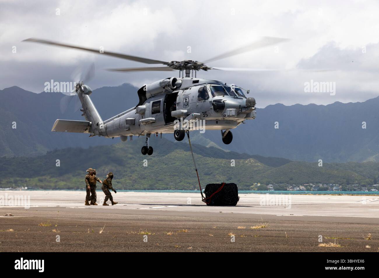 Les spécialistes du soutien au débarquement du corps des Marines des États-Unis avec combat Logistics Company 33, combat Logistics Regiment 37, 3d Marine Logistics Group, III Marine Expeditionary Force, mènent une opération de levage externe avec des pilotes d'hélicoptères MH-60R Seahawk de l'US Navy avec Helicopter maritime Strike Squadron (HSM) 37, Naval Air Force, U.S. Pacific Fleet, à la Marine corps Air Station Kaneohe Bay, Marine corps base Hawaii, le 4 juin 2025. La formation polyvalente a amélioré la préparation des équipes d'appui par hélicoptère, assurant le transport rapide des fournitures et du matériel vers les sites expéditionnaires lors du transport terrestre Banque D'Images