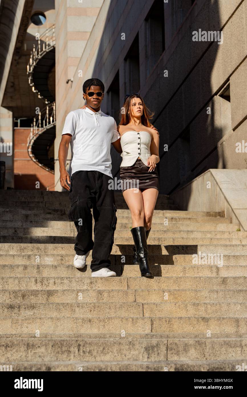 Homme et femme élégants descendant les escaliers extérieurs, mettant en valeur les vêtements à la mode et profitant d'une journée ensoleillée dans la ville Banque D'Images