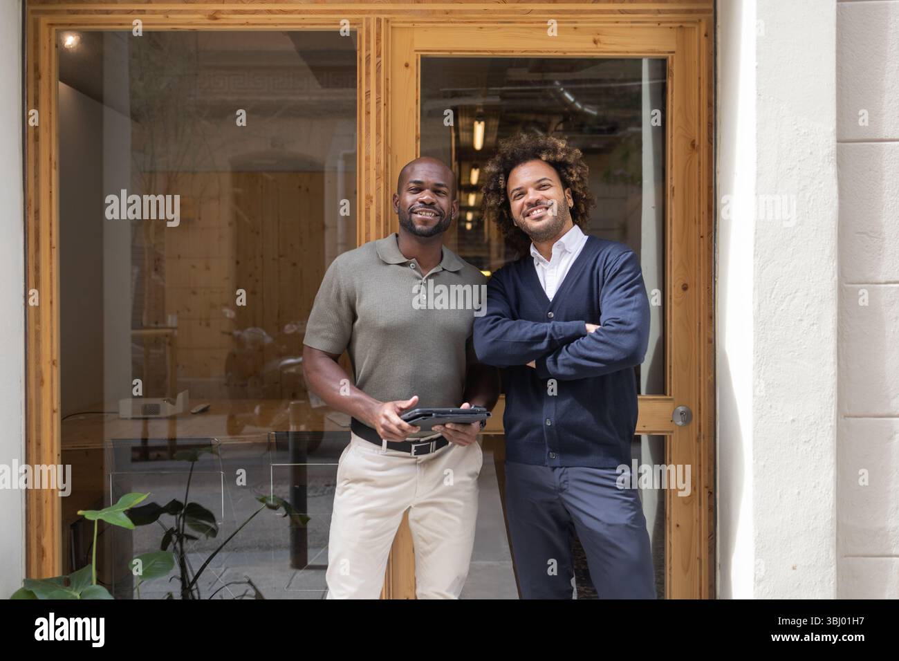 Deux professionnels se tiennent en toute confiance devant un élégant espace de coworking à Barcelone, illustrant la collaboration et les environnements de travail modernes dans une urba Banque D'Images