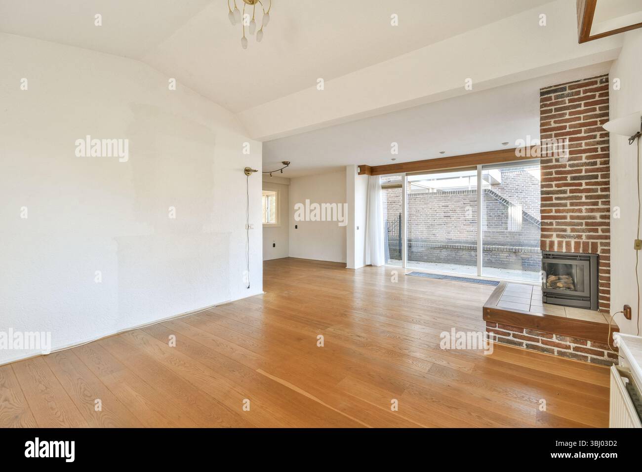 Intérieur lumineux et aéré avec parquet, mur de briques apparentes et grandes fenêtres qui invitent à la lumière naturelle, idéal pour une vie contemporaine s. Banque D'Images