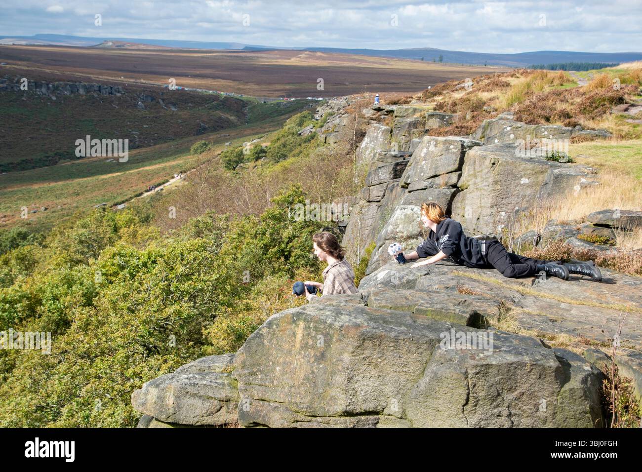 Derbyshire, Royaume-Uni – 28 septembre 2024 : deux adolescents profitent de la vue depuis le sommet d'une falaise à Upper Burbage, Peak District Banque D'Images