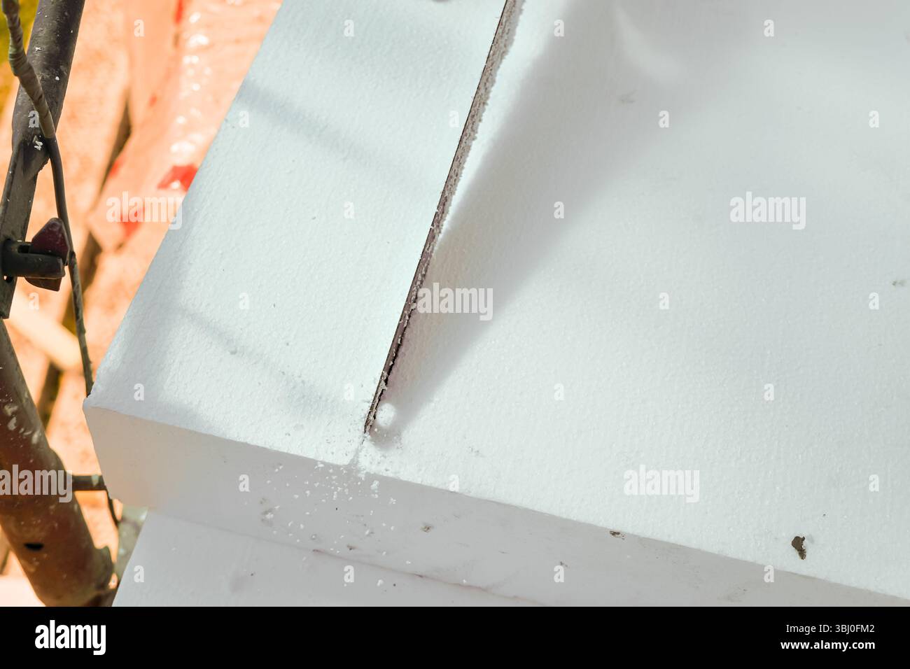 Travailleur de la construction coupant l'isolation thermique en mousse de polystyrène avec une scie à main, gros plan détail d'en haut Banque D'Images