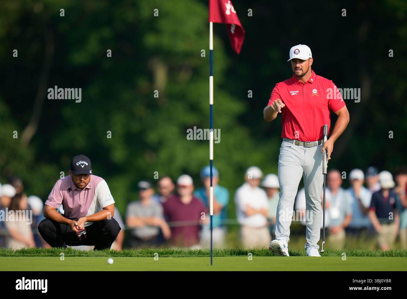 Bryson DeChambeau prepares to putt on the third hole as Xander Schauffele, left, watches during the first round of the U.S. Open golf tournament at Oakmont Country Club Thursday, June 12, 2025, in Oakmont, Pa. (AP Photo/Seth Wenig) Banque D'Images