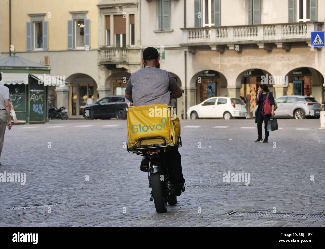 Cycliste de livraison de nourriture à vélo travaillant dans la rue de Bergame avant le dîner Banque D'Images