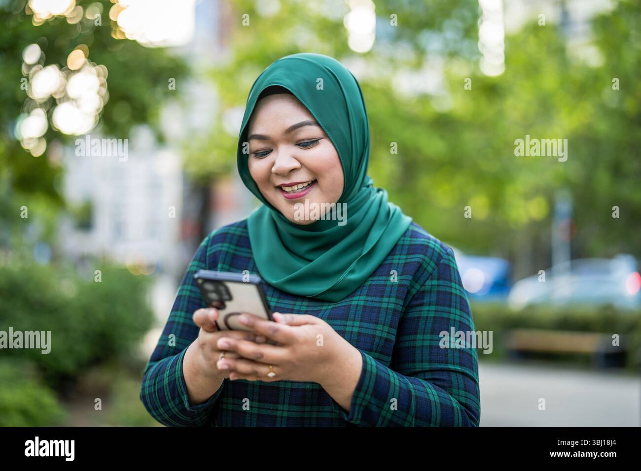 Portrait d'une jeune femme musulmane utilisant un téléphone portable à l'extérieur Banque D'Images