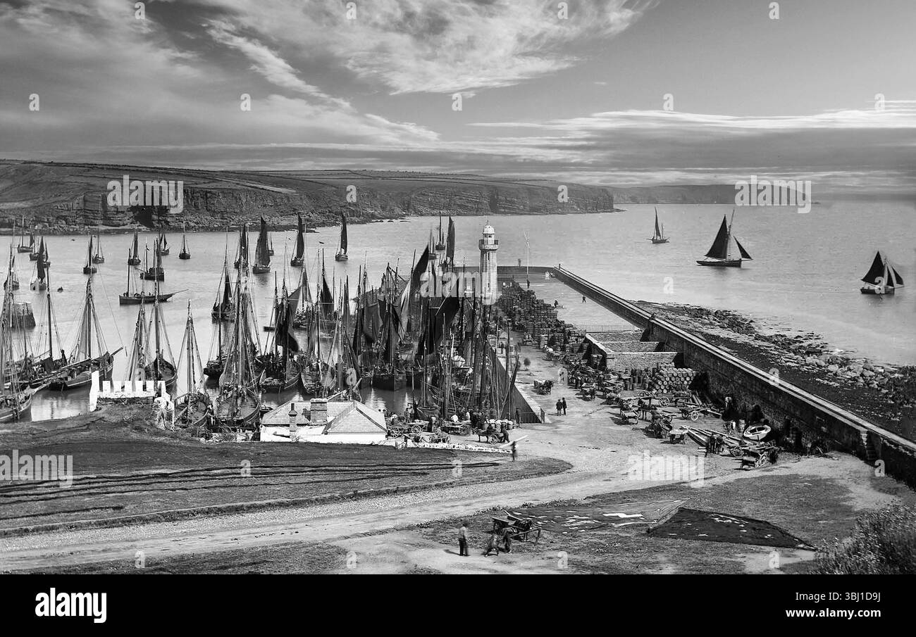 Une photographie de la fin du XIXe siècle représentant la flotte de pêche sent le port de Dunmore East, comté de Waterford, Irlande. Construit en 1814, sur une conception d'Alexander Nimmo, un ingénieur écossais, le port comprenait une jetée massive ou un quai avec un élégant phare à la fin. Au 21ème siècle, le port est l'un des cinq ports de pêche nationaux désignés, et a le deuxième chiffre le plus élevé pour les débarquements de poissons après Killybegs. Banque D'Images