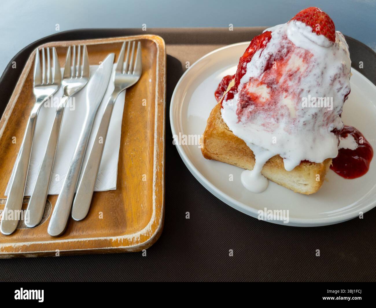 Irrésistible bingsu à la crème de fraise sur pain grillé, servi avec fourchette et couteau, idéal pour les menus de café, les blogs alimentaires ou les photos. Frais, crémeux, a Banque D'Images