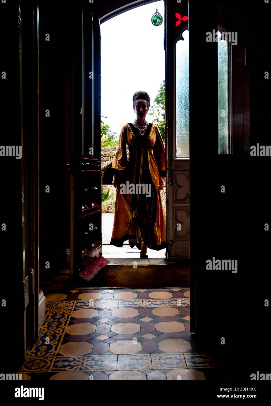 Une femme dans une robe d'or se tient dans une porte. Banque D'Images