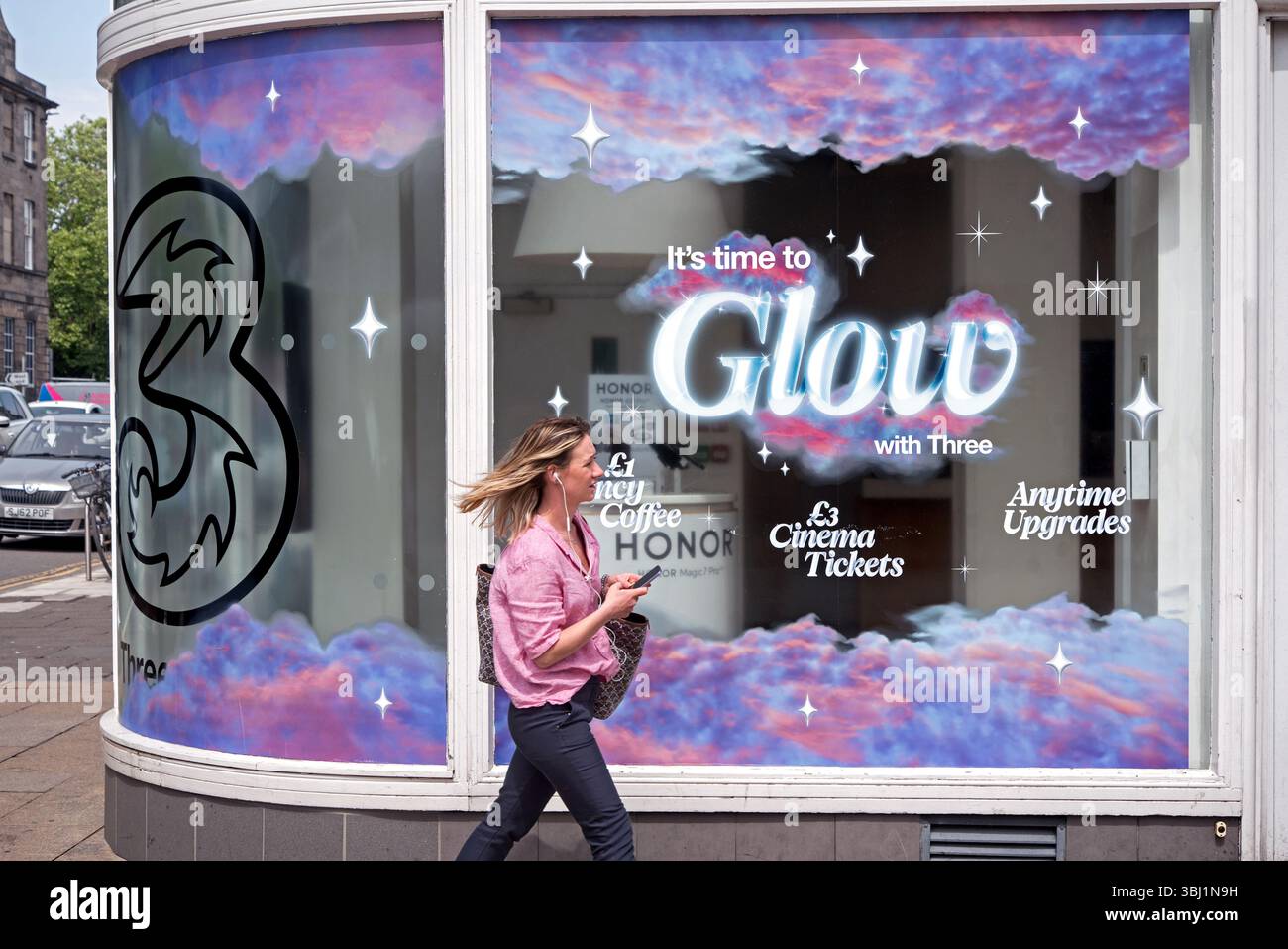 Jeune femme marchant par une succursale de 3 Three Network service Provider sur Princes Street, Édimbourg, Écosse, Royaume-Uni. Banque D'Images