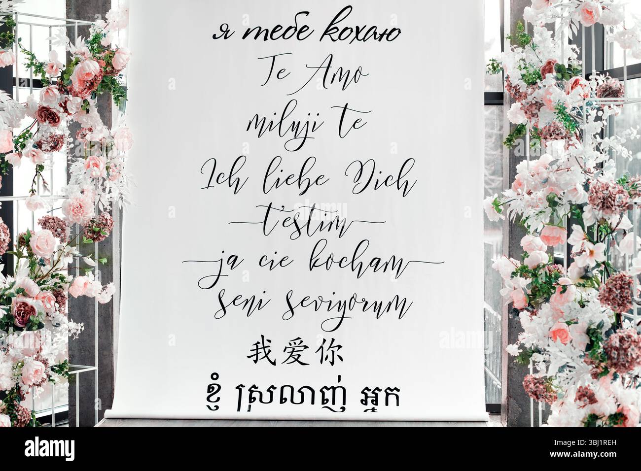 Photo d’un véritable lieu de mariage avec des décorations florales et une toile de fond romantique mettant en vedette « je t’aime » écrit en plusieurs langues. Banque D'Images