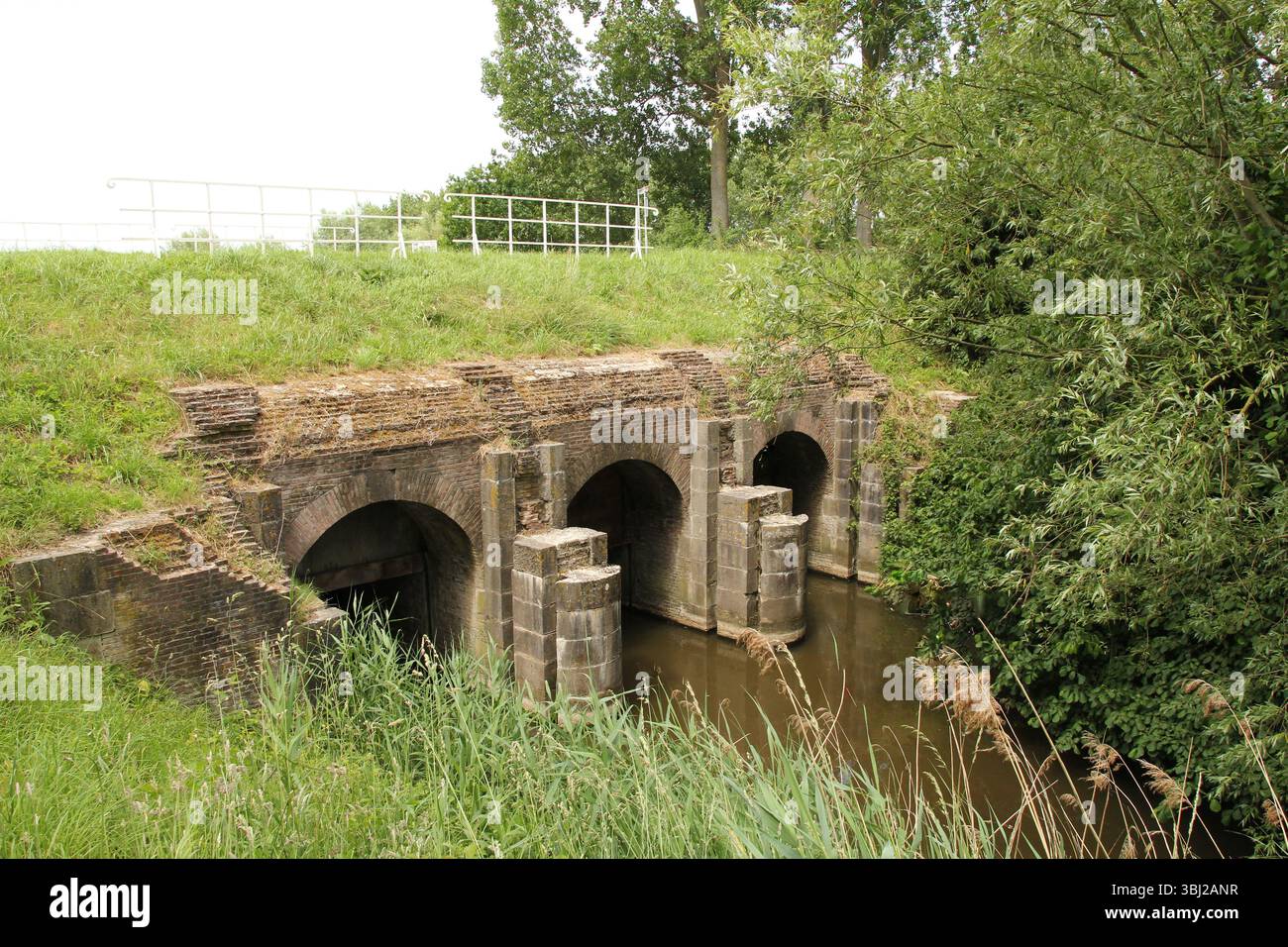 un canal de drainage avec une écluse maritime historique dans la campagne hollandaise en zélande pour drainer les polders dans l'arrière-pays et la rétention d'eau douce Banque D'Images