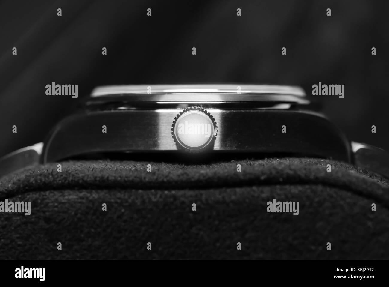 Une vue détaillée en noir et blanc d'une couronne de montre-bracelet de luxe mettant en évidence sa texture et son savoir-faire, sur un fond sombre adouci, empha Banque D'Images