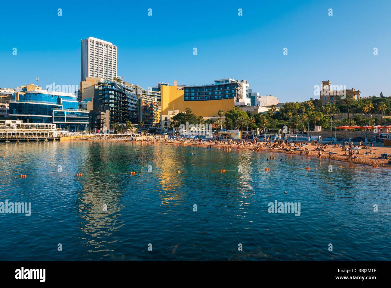 Belle vue panoramique de la soirée à la baie de George à Saint Julian's (San Ġiljan), Malte, avec beaucoup de gens appréciant la plage de sable Banque D'Images